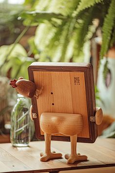 a wooden toy sitting on top of a table next to a vase and potted plant