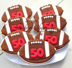 decorated cookies in the shape of footballs are on a white plate with red lettering