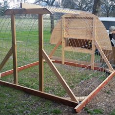 a man standing next to a chicken coop in the grass with another person looking at it