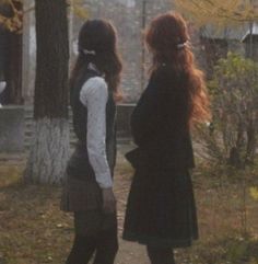 two young women standing next to each other on a path in the woods at dusk