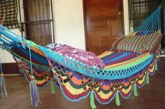 a colorful hammock with tassels hanging from it's sides in front of a door