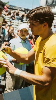 a man signing autographs for fans at a baseball game in front of an audience