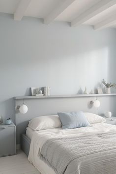 a white bed sitting in a bedroom next to a wall mounted shelf with lights on it