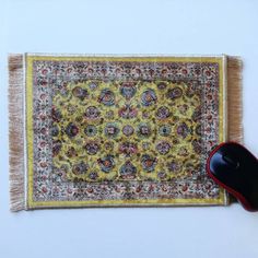 a computer mouse sitting on top of a rug next to a computer mouse pad with a yellow and red design