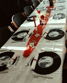 a long table is set with black and white plates, silverware, and red napkins