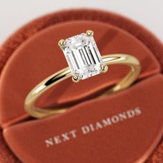 a close up of a ring with a diamond in it on a red velvet box