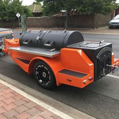 an orange and black grill truck parked on the side of the road next to a street