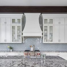 a kitchen with marble counter tops and white cabinets