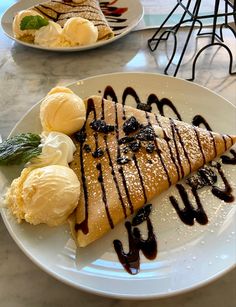 two plates with desserts on them sitting on a marble counter top, one has ice cream and the other has chocolate sauce