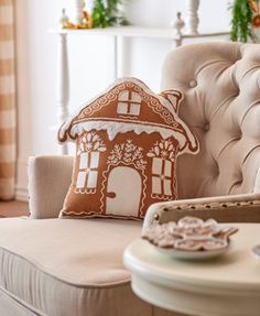 a gingerbread house pillow sitting on top of a couch next to a coffee table