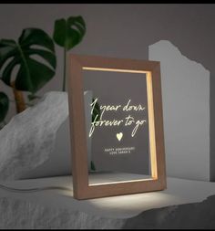 a wooden frame sitting on top of a white table next to a potted plant