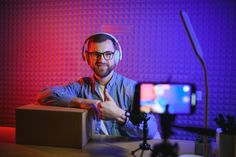 a man with headphones on sitting in front of a camera and recording his video