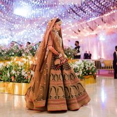 a woman in a brown and gold bridal gown is walking down the aisle at a wedding