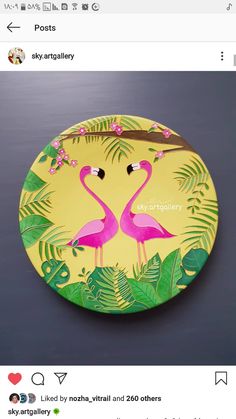 a yellow plate with two pink flamingos on it and green leaves around the edges