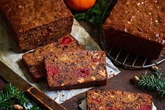 slices of fruitcake sitting on top of parchment paper next to a knife and orange