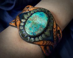 a close up of a person's arm wearing a bracelet with a turquoise stone on it