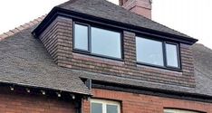 a red brick house with three windows and a cat sitting on the window sill