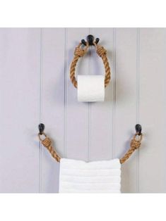 two white towels hanging on the wall next to a toilet paper holder with rope wrapped around it