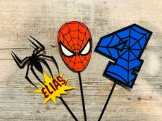 three spiderman cake toppers on a wooden table