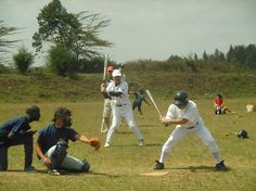 a group of people playing baseball in a field with one holding a bat and the other holding a glove