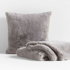 a blanket and pillow sitting next to each other on a white surface with a wall in the background