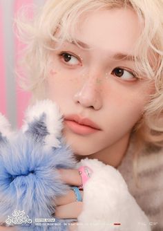 a woman with blonde hair holding a stuffed animal in front of her face and looking at the camera