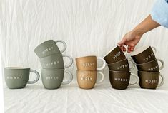 four coffee mugs with the words hubby written on them are being held by a woman's hand