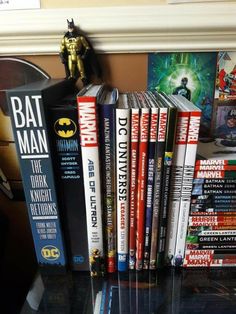 a bunch of books sitting on top of a table next to a batman figurine