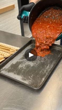 a person pouring sauce into a pan with crackers