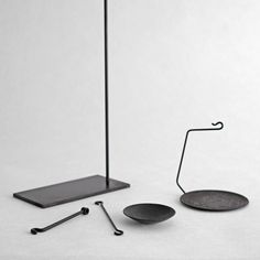 three black metal objects on a white surface, one with a hook and the other without