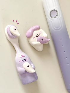 two toothbrushes with faces painted on them next to an electric toothbrush holder