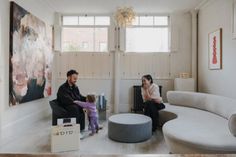 a man and woman sitting in a living room with a child on the couch next to them