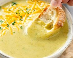 a person dipping cheese into a bowl of soup