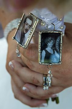 a bride holding two wedding rings with pictures attached to the ring, while wearing a tiara