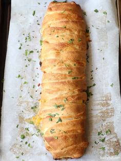 a loaf of bread sitting on top of a baking pan covered in cheese and herbs