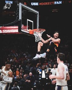 a basketball player jumping up into the air to dunk a ball in front of other players