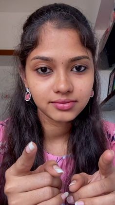 a girl with long hair wearing pink and white nail polish holding her fingers up to the camera