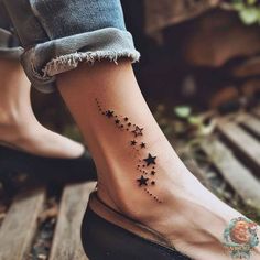 a woman's foot with stars tattooed on the side of her left leg and ankle