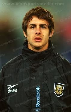 a young man wearing a black jacket standing in front of a blurry background and looking at the camera