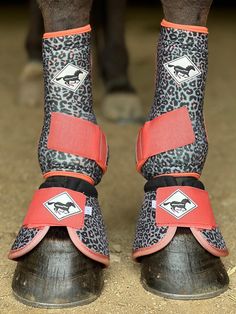 the legs and feet of a person wearing boots with animal prints on them, standing in front of a horse