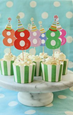 cupcakes with birthday hats on top are sitting on a cake plate in front of polka dot tablecloth