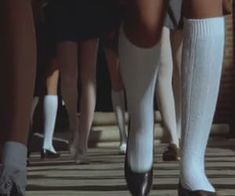 there are many people walking down the street wearing white socks and knee high socks with black heels