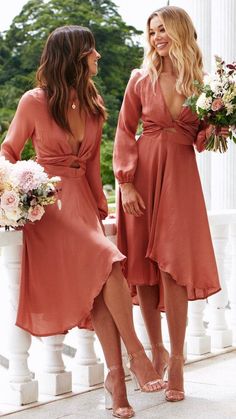 two women standing next to each other wearing dresses and holding bouquets in their hands