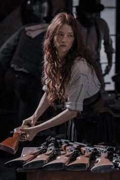 a woman standing in front of a table full of shoes and holding a wooden object