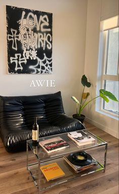 a living room with a black leather couch and coffee table in front of a painting