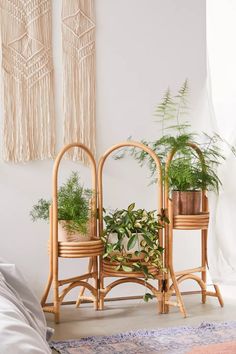 two wicker plant stands with plants in them on a rug next to a bed