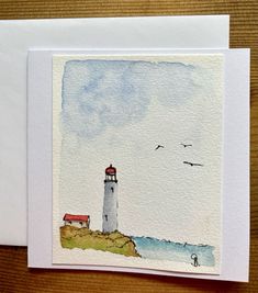 two cards with watercolor drawings of lighthouses on the shore and seagulls flying over them