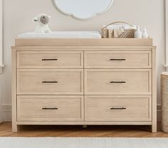 a baby's room with a dresser, mirror and stuffed animal on the floor