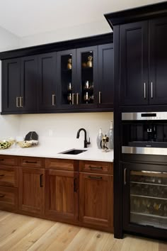 a kitchen with black cabinets and white counter tops, an oven in the corner and wooden flooring