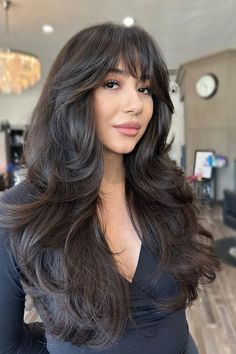 This curtain bang hairstyle has softly layered bangs that shape the facial features, parted in the middle to smoothly join the trailing sections of hair. The full waves add a dash of flair and motion, making it a flexible look that easily shifts between day and evening. The deep, dark hue of the hair boosts the - Click to see more of Stay Ahead of the Curve: 30 Curtain Bang Haircuts That Will Dominate 2024 and follow us for more hairstyle ideas. // Photo Credit: Instagram @realbeautybycynthia Bang Haircuts, Blond Pony, Layered Bangs, Layered Hair With Bangs, Hair 2024, Long Dark Hair